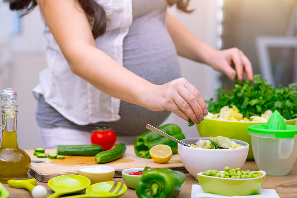 Pregnant woman preparing a healthy meal.